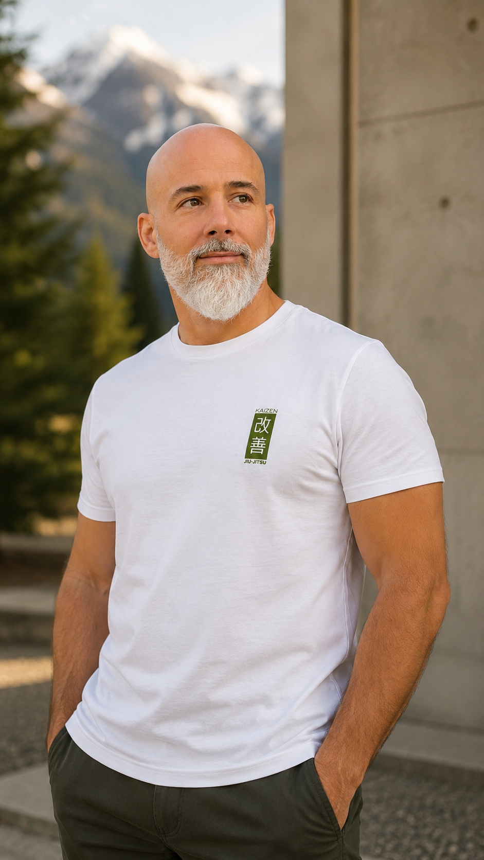 Mann im weissen Kaizen Jiu-Jitsu T-Shirt vor Betonwand – Bio-Baumwolle, mossgrünes Brustlogo, Frontansicht