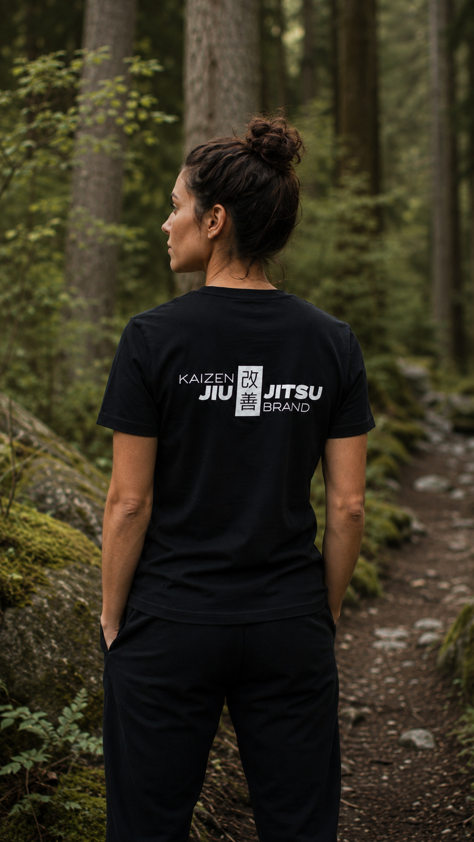 Frau im schwarzen Kaizen T-Shirt von hinten – 改善 Rückenlogo, Waldweg, Rückansicht