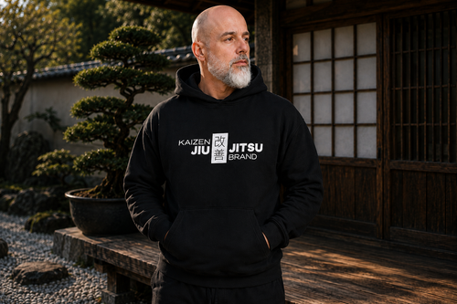 Mann im schwarzen Kaizen Black Label Hoodie in einem japanischen Garten – nachhaltige BJJ Streetwear, Frontansicht