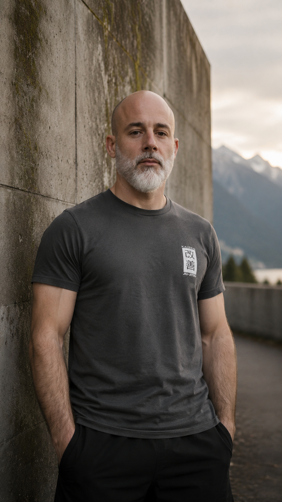Mann im grauen Kaizen T-Shirt an einer Betonwand – Bio-Baumwolle, Frontansicht